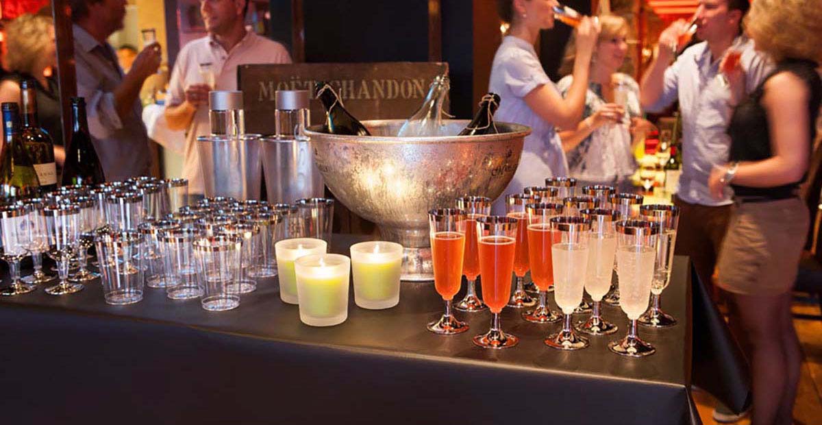 Milieubild Catering: Gläser, Kerzen, Sektkübel, feiernde Menschen